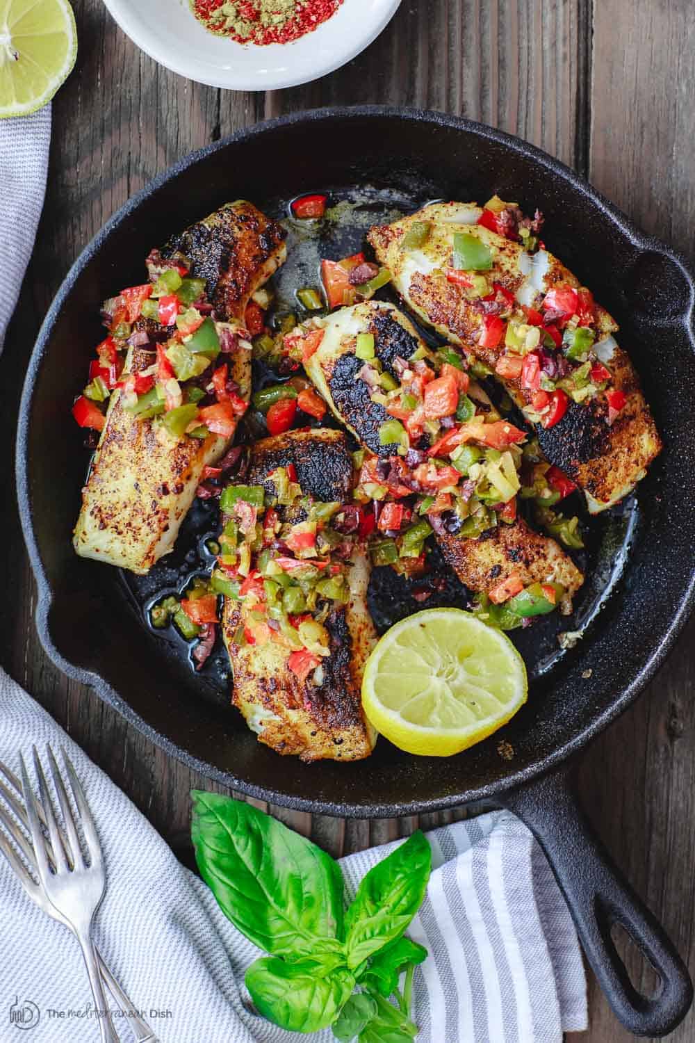Mediterranean sea bass seared in a skillet with a medley of bell peppers served on top