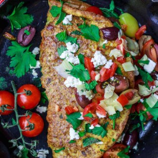 Loaded Mediterranean Omelette Recipe | The Mediterranean Dish. Perfectly-seasoned omelette loaded with fresh herbs and Mediterranean favorites like tomato, artichokes, feta and more. There is a secret ingredient that makes this omelette a little extra airy and fluffly! From TheMediterraneanDish.com