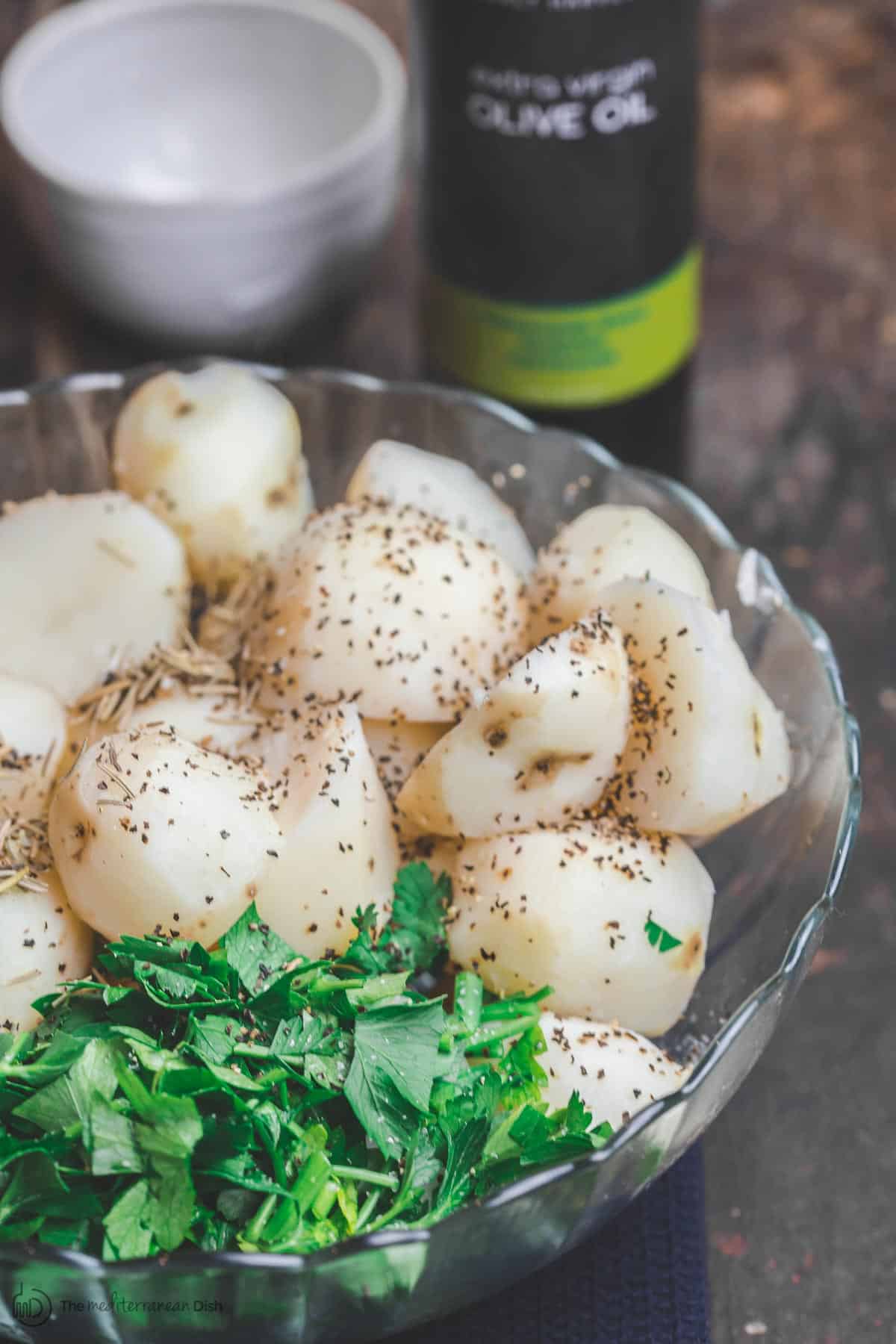 Boiled potatoes in a bowl with spices and fresh parsley. Olive oil ready for use