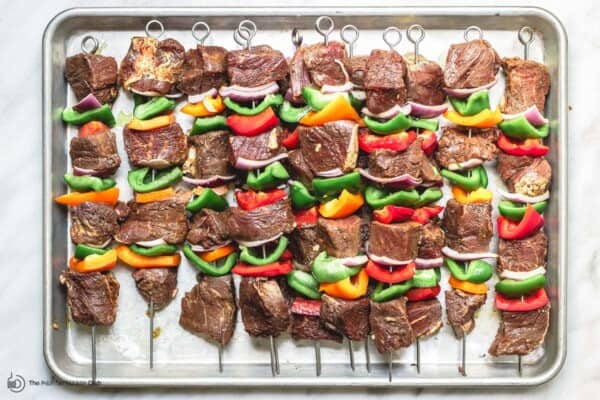 uncooked beef kabobs on a tray ready for grilling