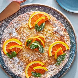 orange cardamom olive oil cake topped with orange slices.