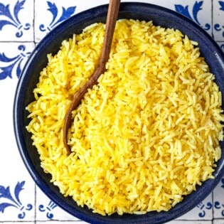 saffron rice in a bowl with a wooden spoon.