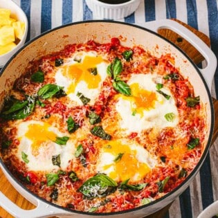 a skillet of eggs in purgatory next to a jar of jam.