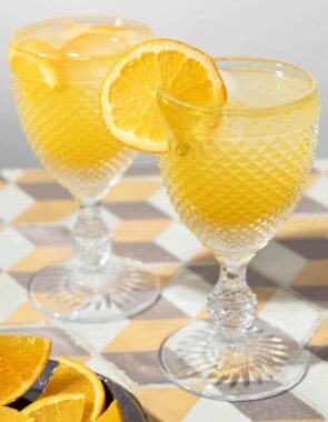 two glasses of agua de valencia garnished with orange slices.