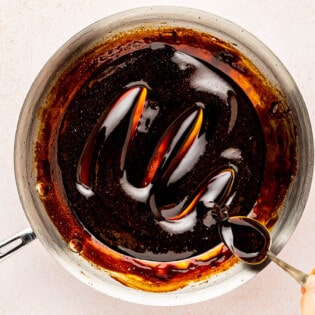 balsamic glaze being stirred with a spoon in a skillet.