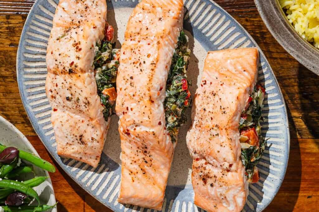 An overhead photo of three stuffed salmon fillets on a serving platter.