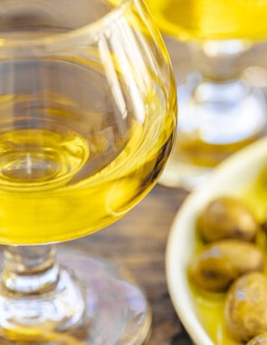 a closeup of a small glass of olive and and a small plate of green olives.