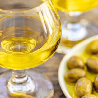 a closeup of a small glass of olive and and a small plate of green olives.