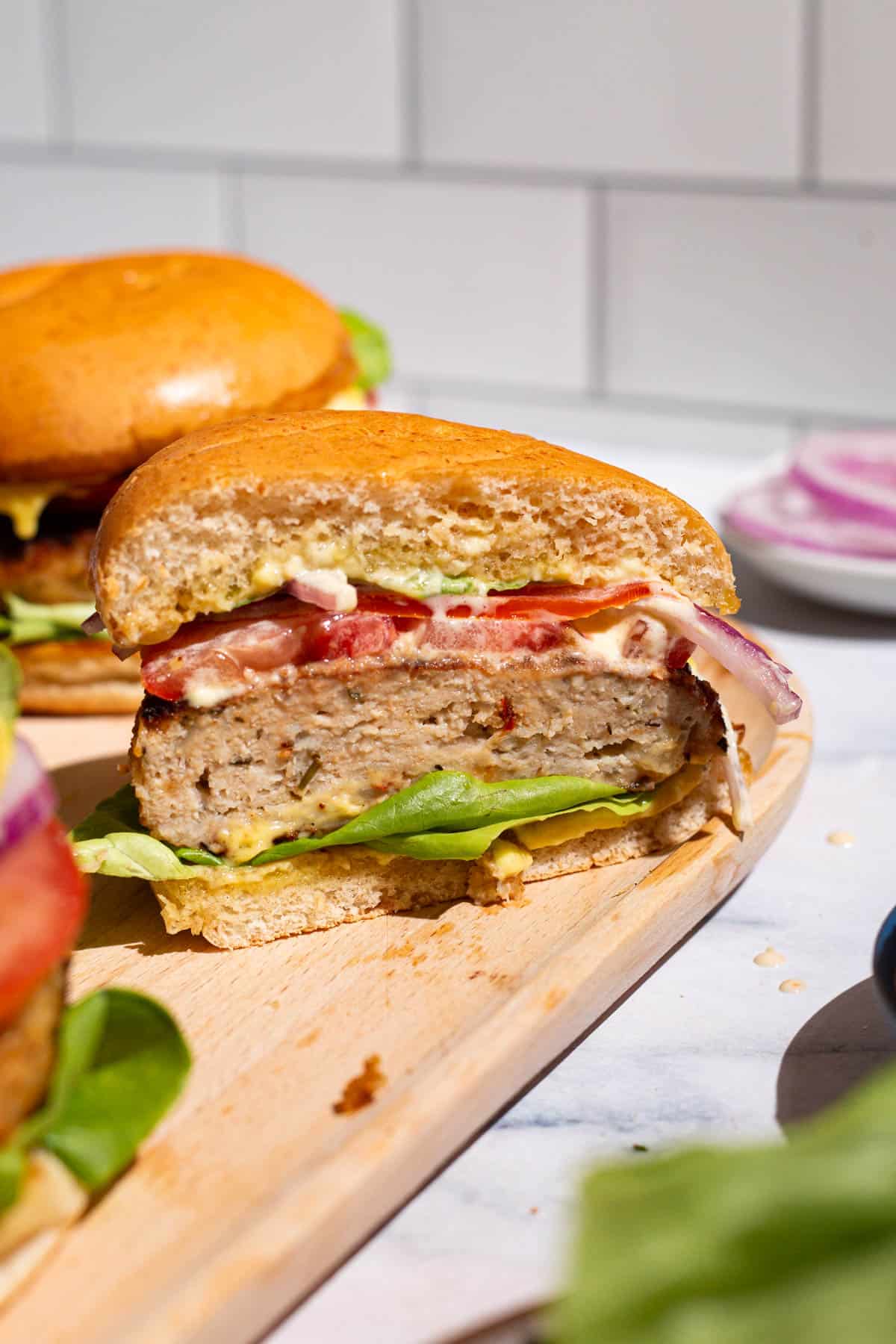 A close up of half of a chicken burger on a wooden serving platter.