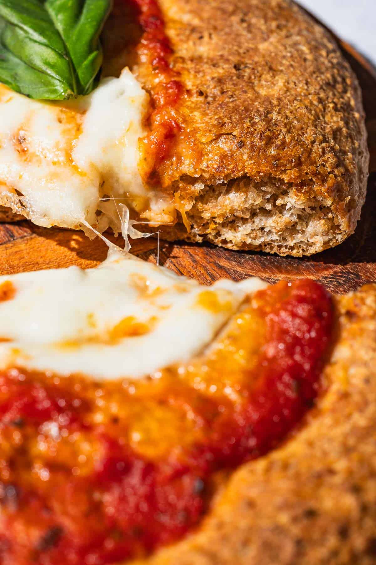 A very close up photo of 2 slices of pizza made with a whole wheat crust.