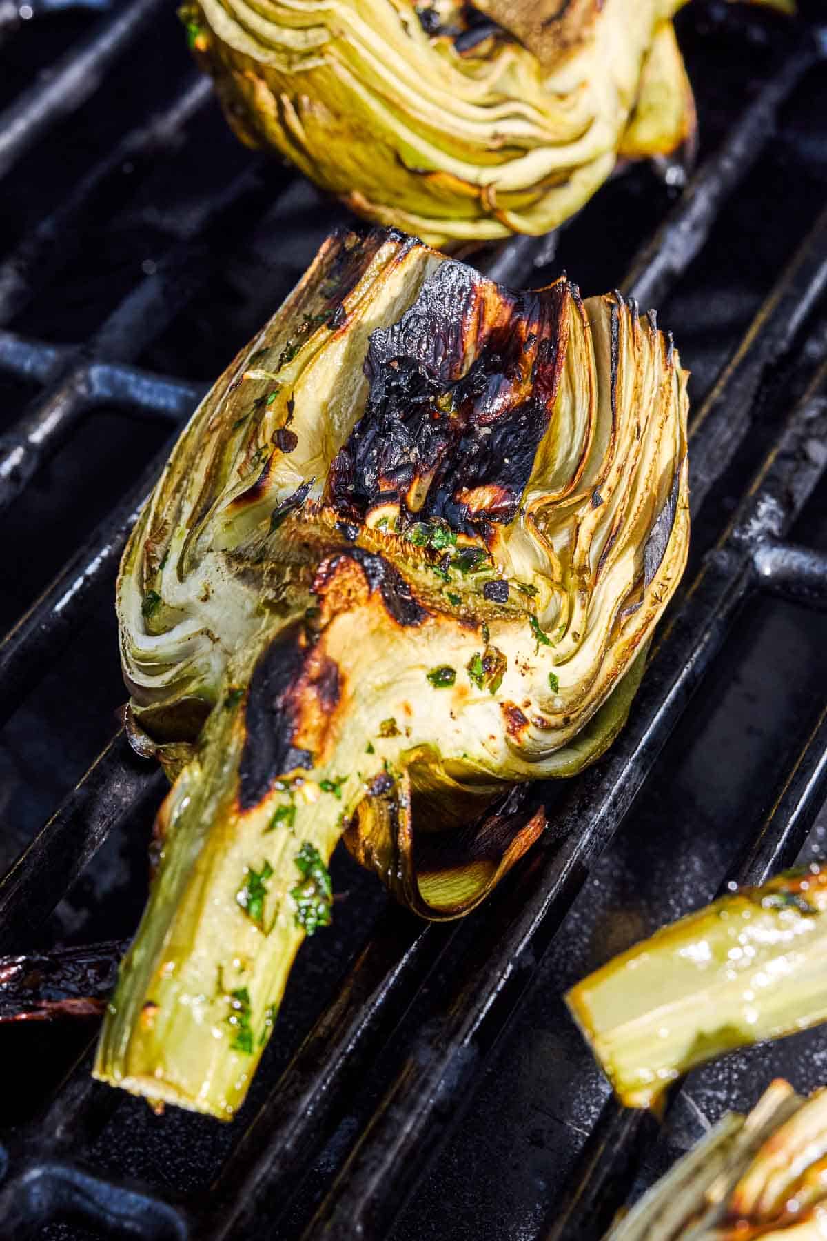A close up of an artichoke quarter being grilled on a grill.
