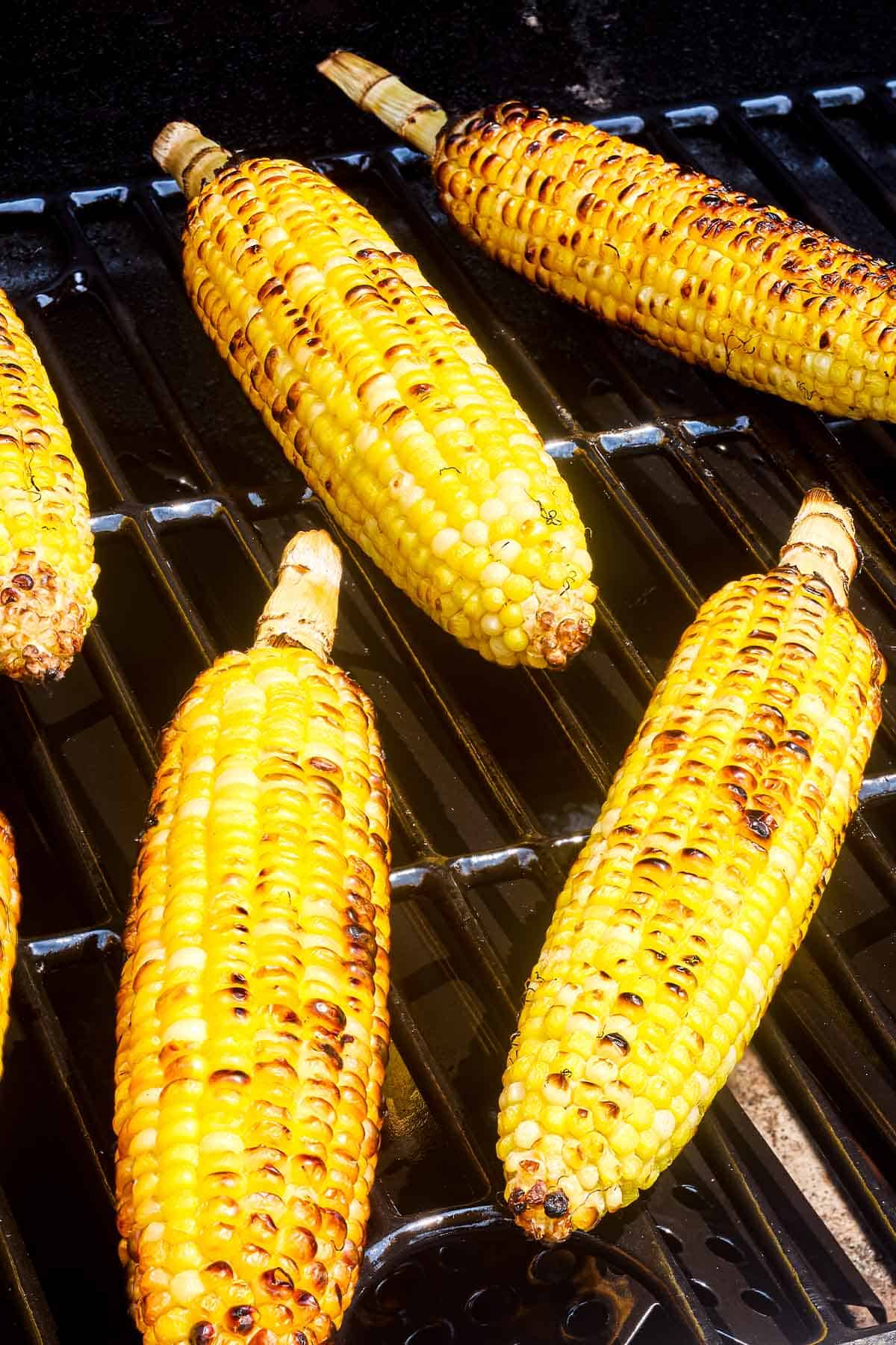 A close up of 4 corncobs being grilled on a grill.