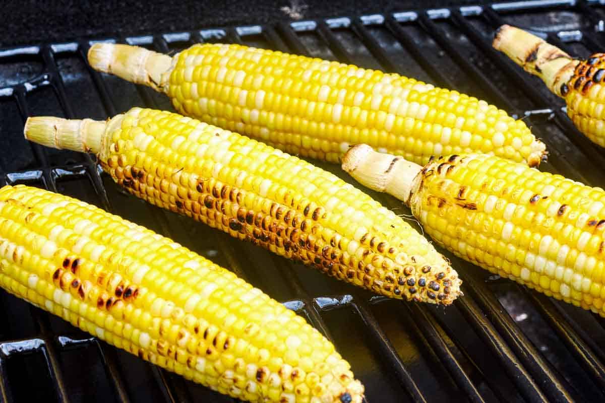 A close up of 5 corncobs being grilled on a grill.
