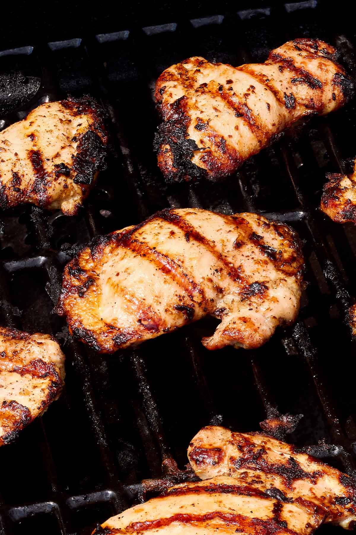 Chicken thighs being grilled on an outdoor grill.