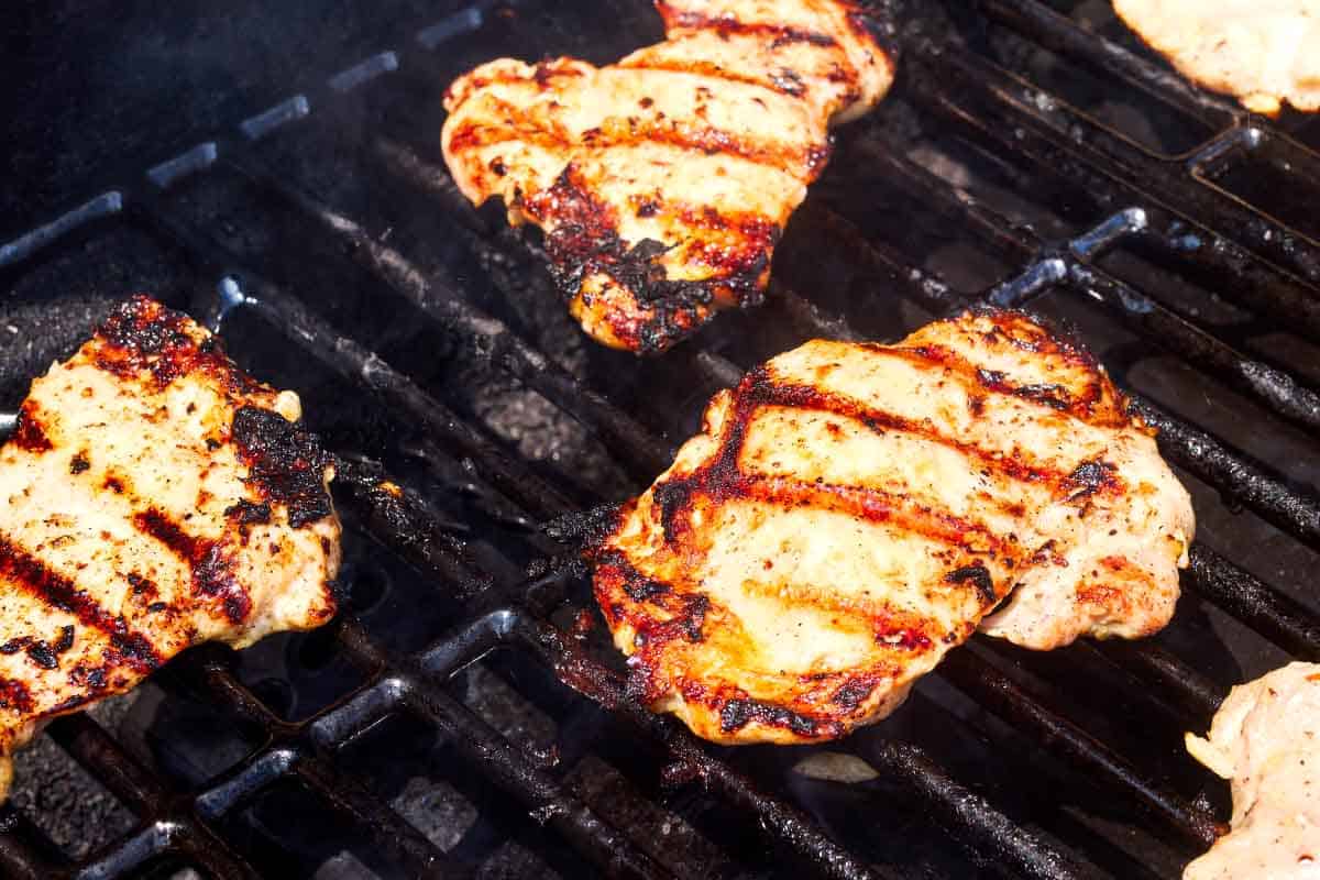 Chicken thighs being grilled on an outdoor grill.