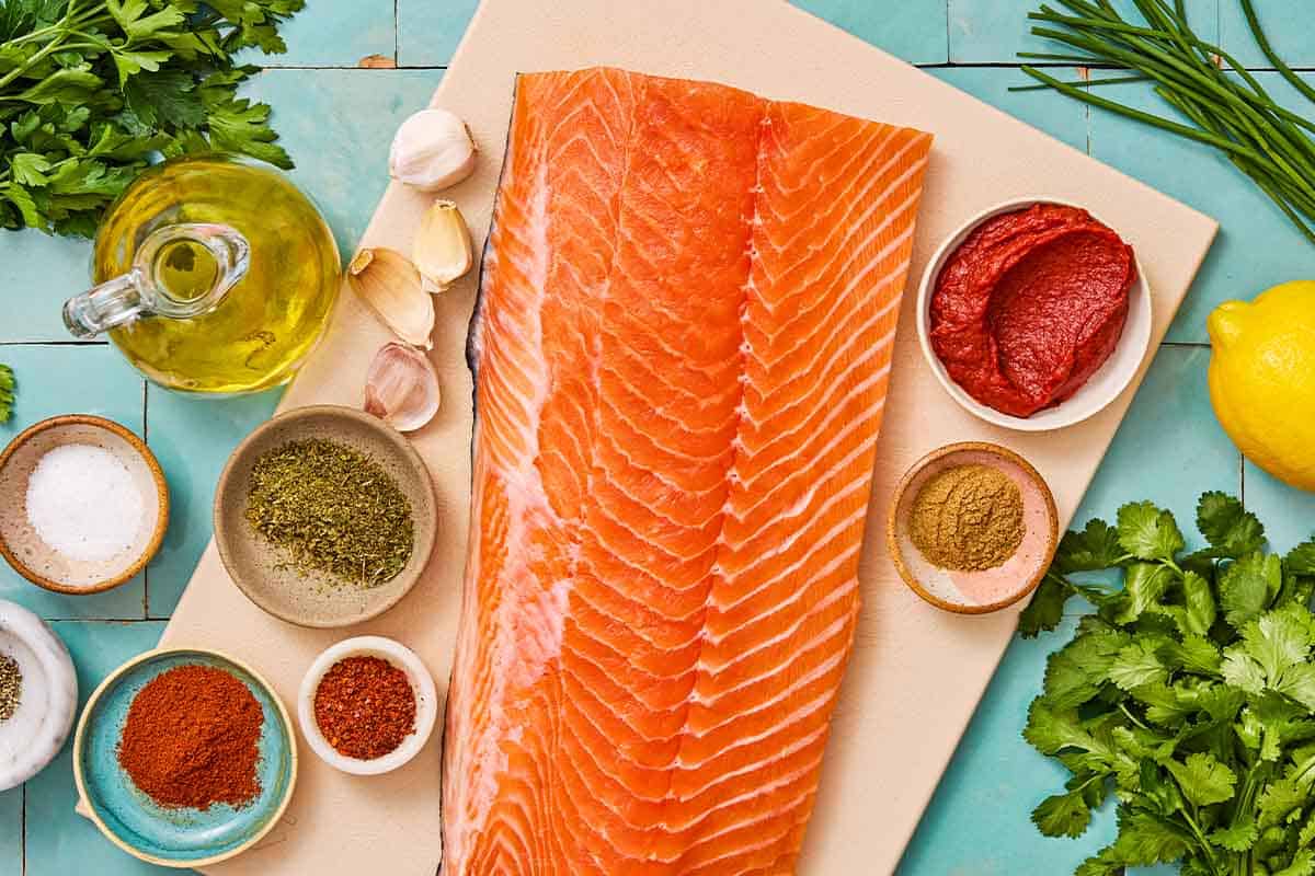 Ingredients for Turkish style salmon including salmon, olive oil, turkish red pepper paste, oregano, smoked paprika, aleppo pepper, lemon, garlic, salt, black pepper, parsley, chives and cilantro.