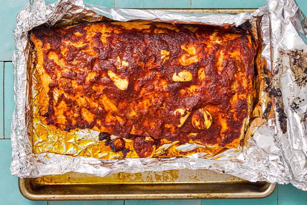 Baked Turkish style salmon on a foil-lined baking sheet.