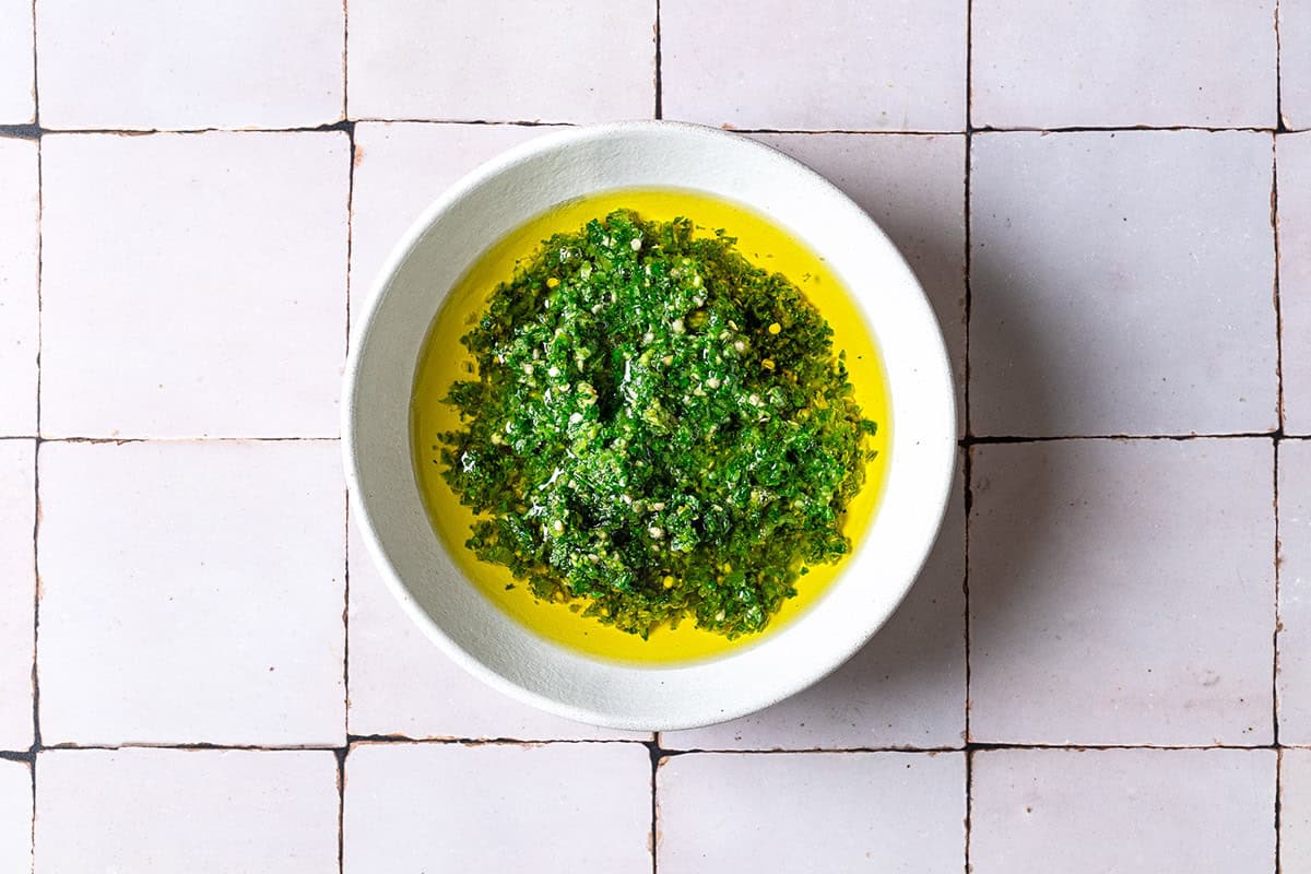 The cilantro paste in a bowl with olive oil just before being completely mixed together.