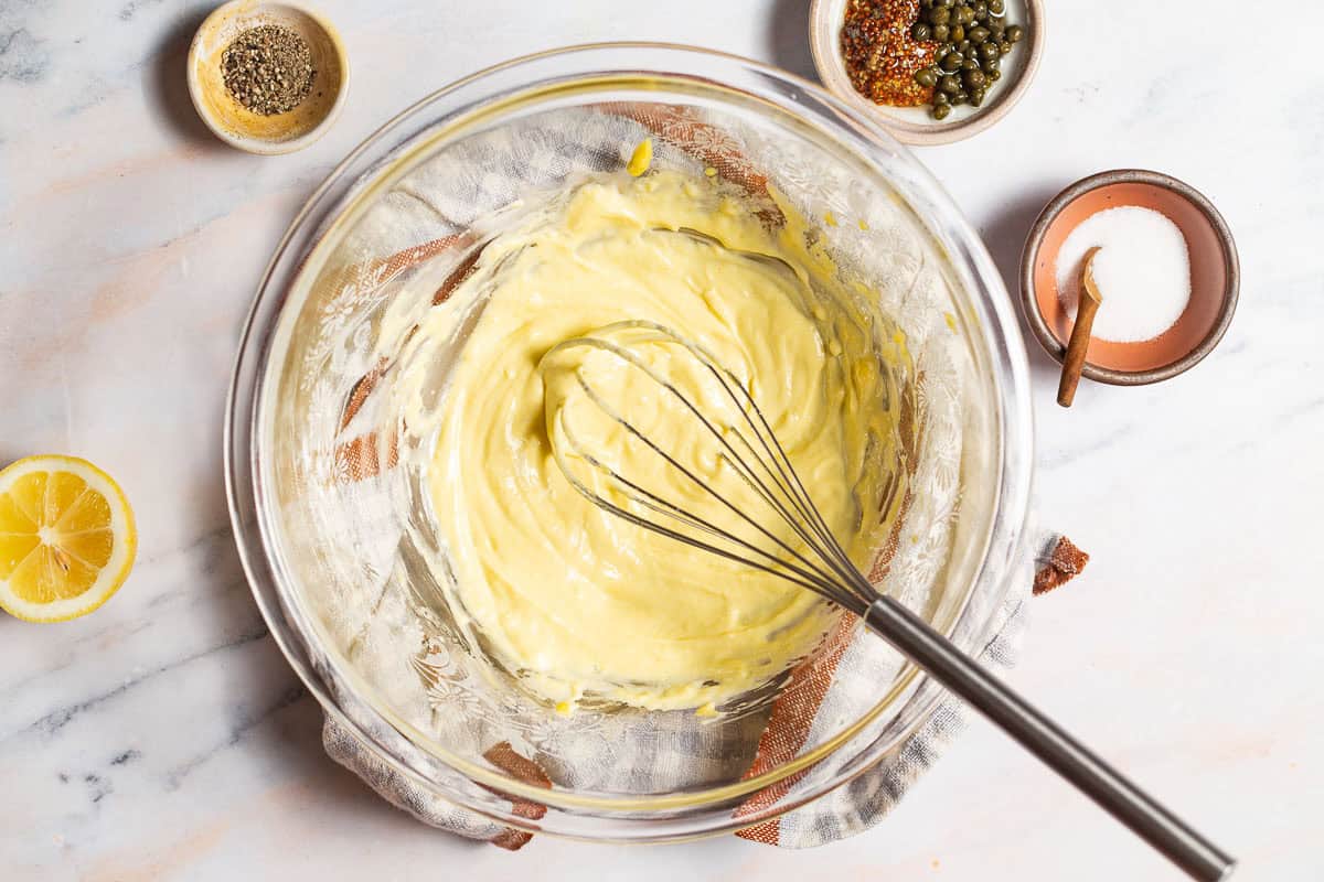 egg yolk in a mixing bowl after the oil has been incorporated, showing the thick texture and lighter yellow color.