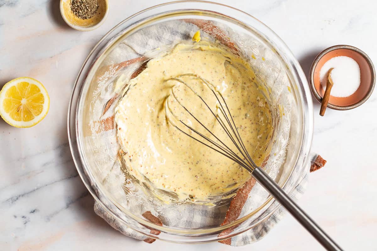 shrimp salad dressing in a glass mixing bowl after the dijon and lemon juice have been whisked in.