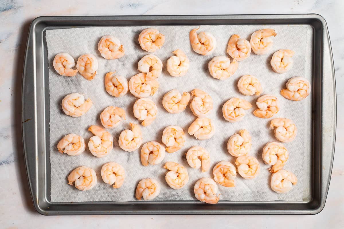 shrimp drying on a paper towel-lined sheet tray.