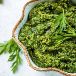 A close up of carrot top pesto in a bowl.