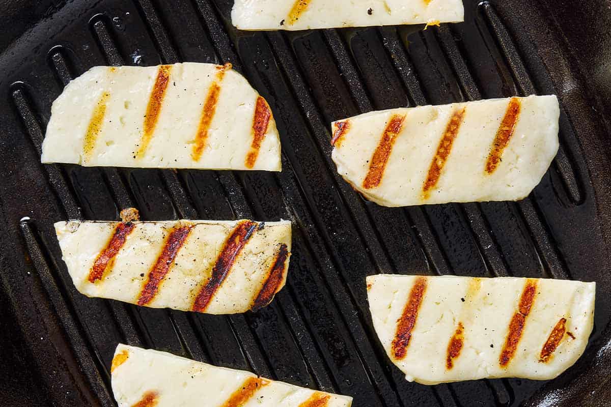 Slices of halloumi being grilled on a griddle.