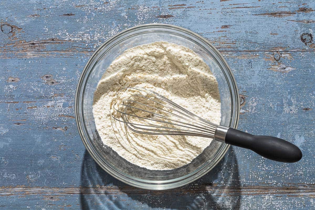 The dry ingredients for the lemon ricotta cake in a mixing bowl with a whisk.