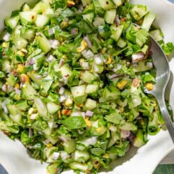 An overhead photo of a bowl of cucumber salsa with a spoon.