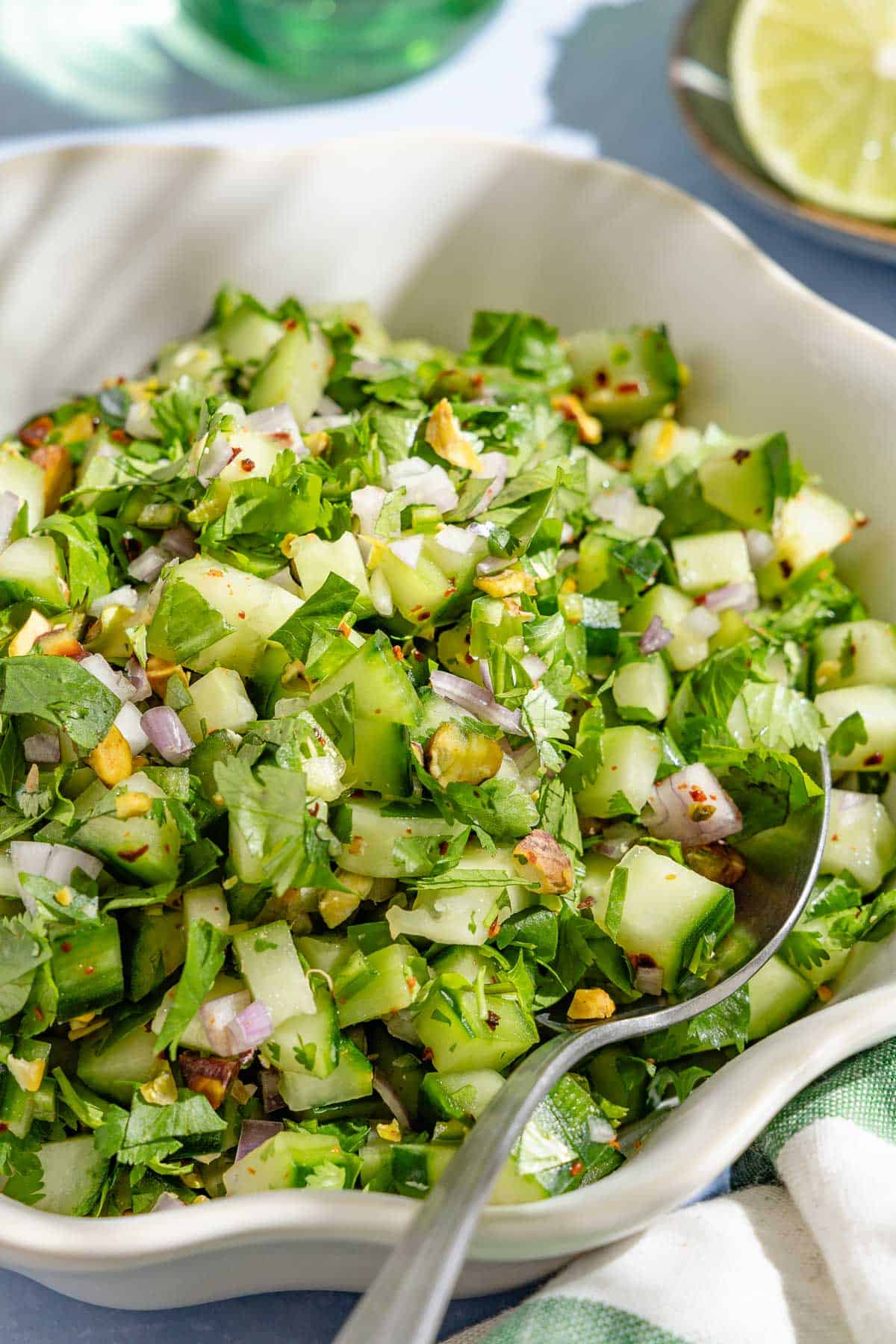 A close up of a bowl of cucumber salsa with a spoon.