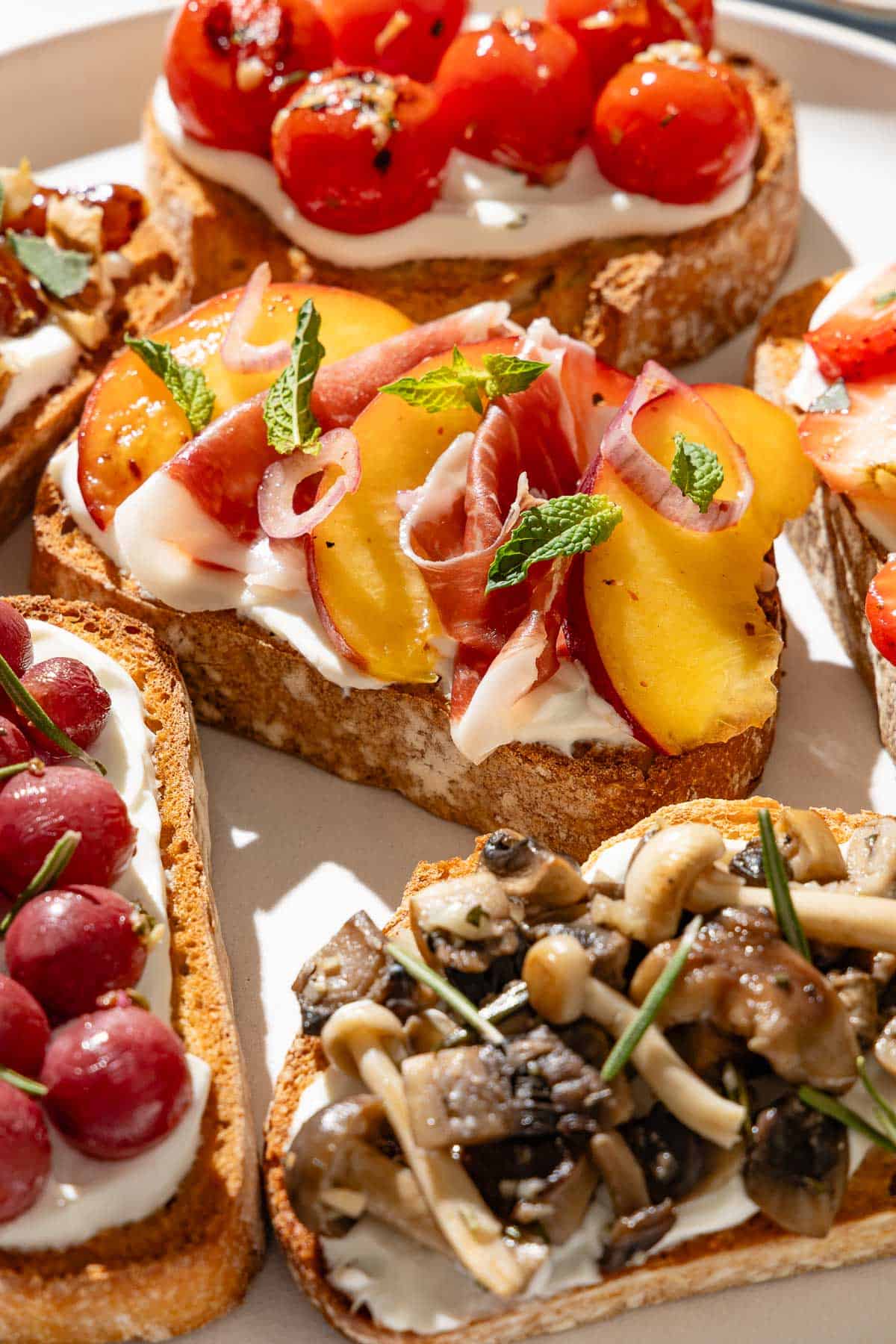 A close up of an assortment of ricotta toasts on a serving plate.