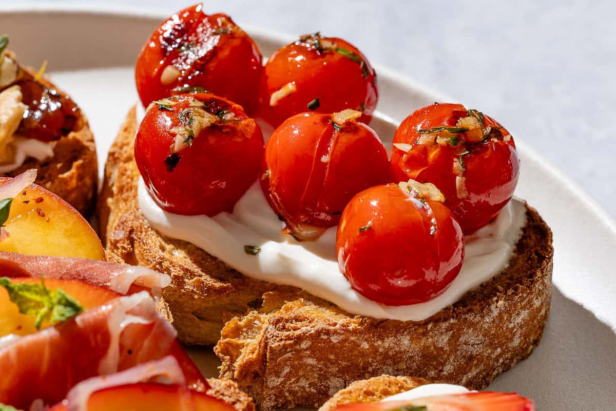 A close up of the blistered cherry tomato ricotta toast on the serving plate.