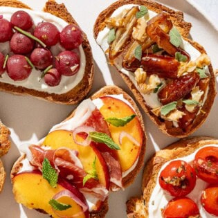 An overhead close up photo of an assortment of the ricotta toasts on a serving plate.