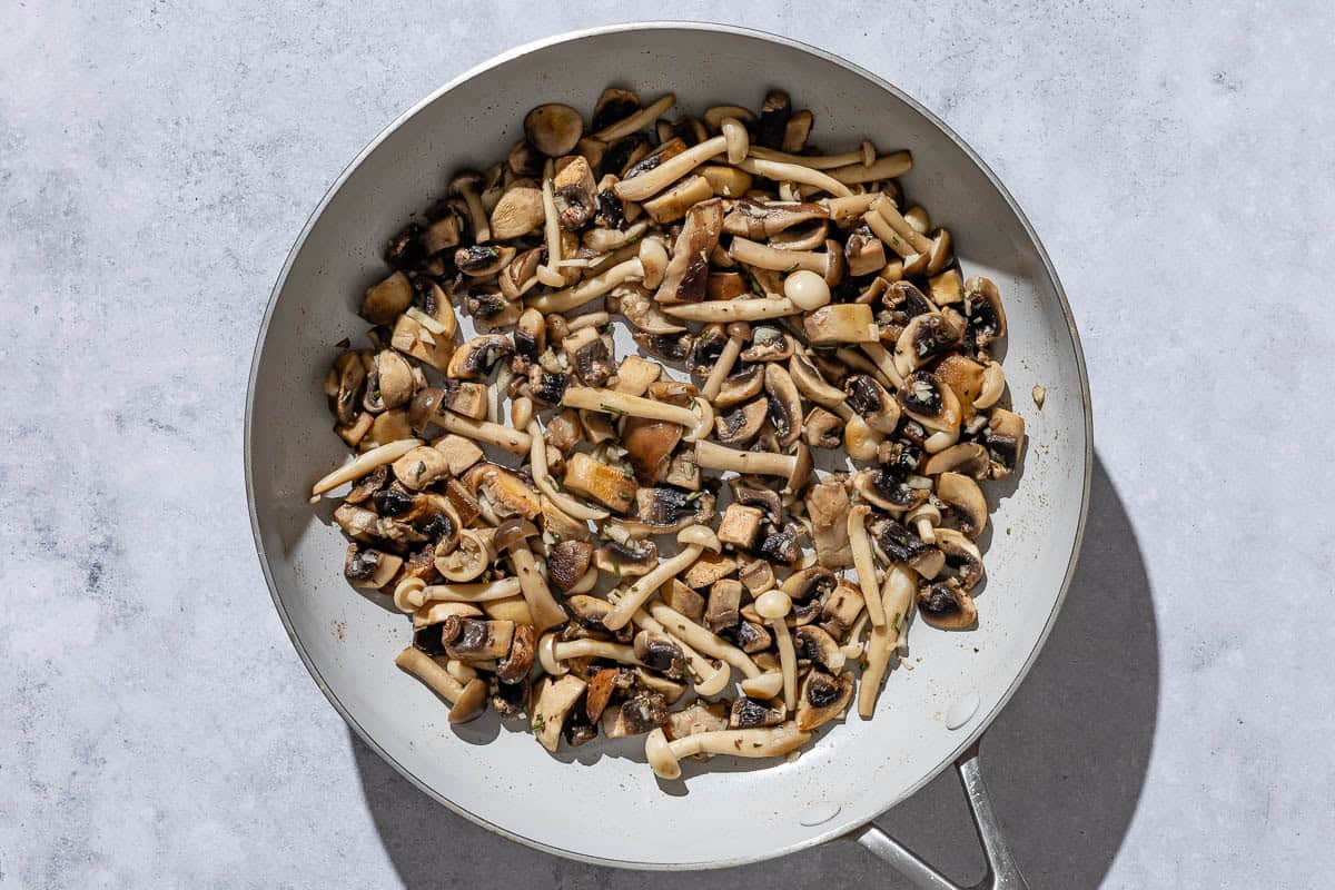 Mushrooms being sauteed in a skillet.