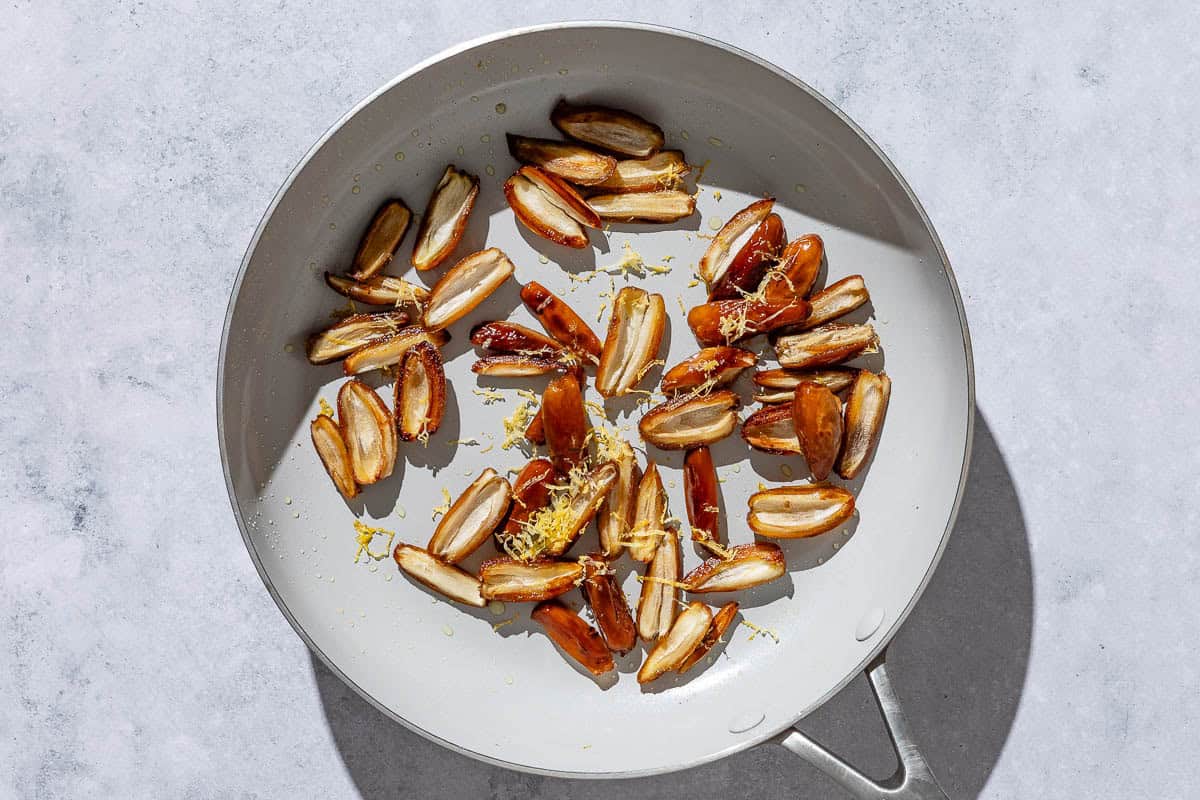 Sliced dates topped with lemon zest being warmed in a skillet.