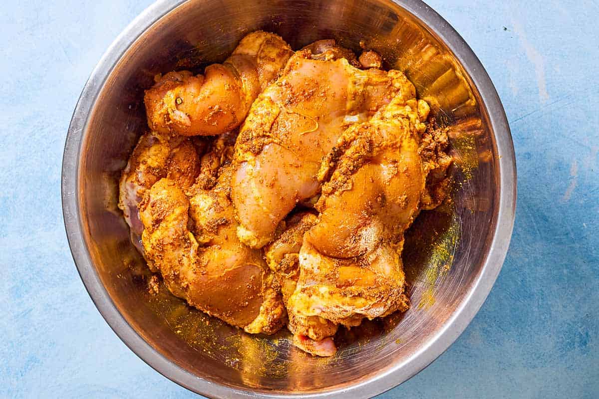 The chicken thigh marinating in a large bowl.