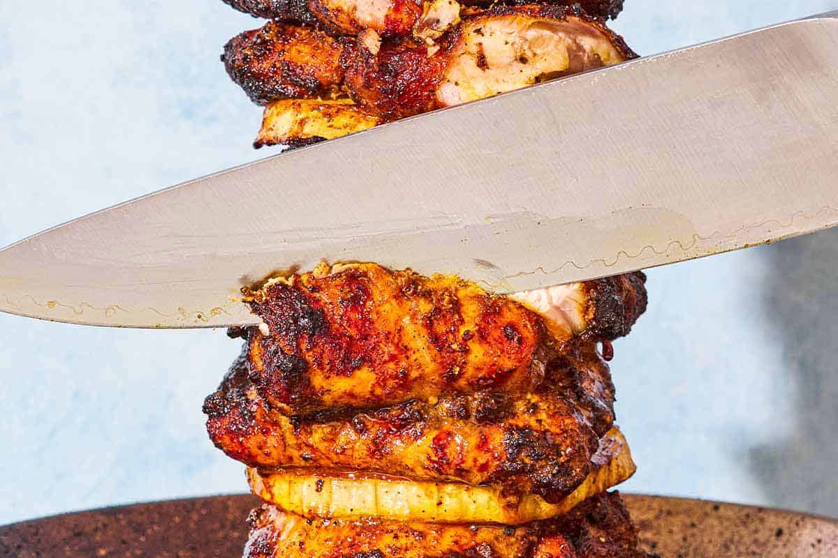 A close up of a knife cutting into the grilled chicken shawarma.