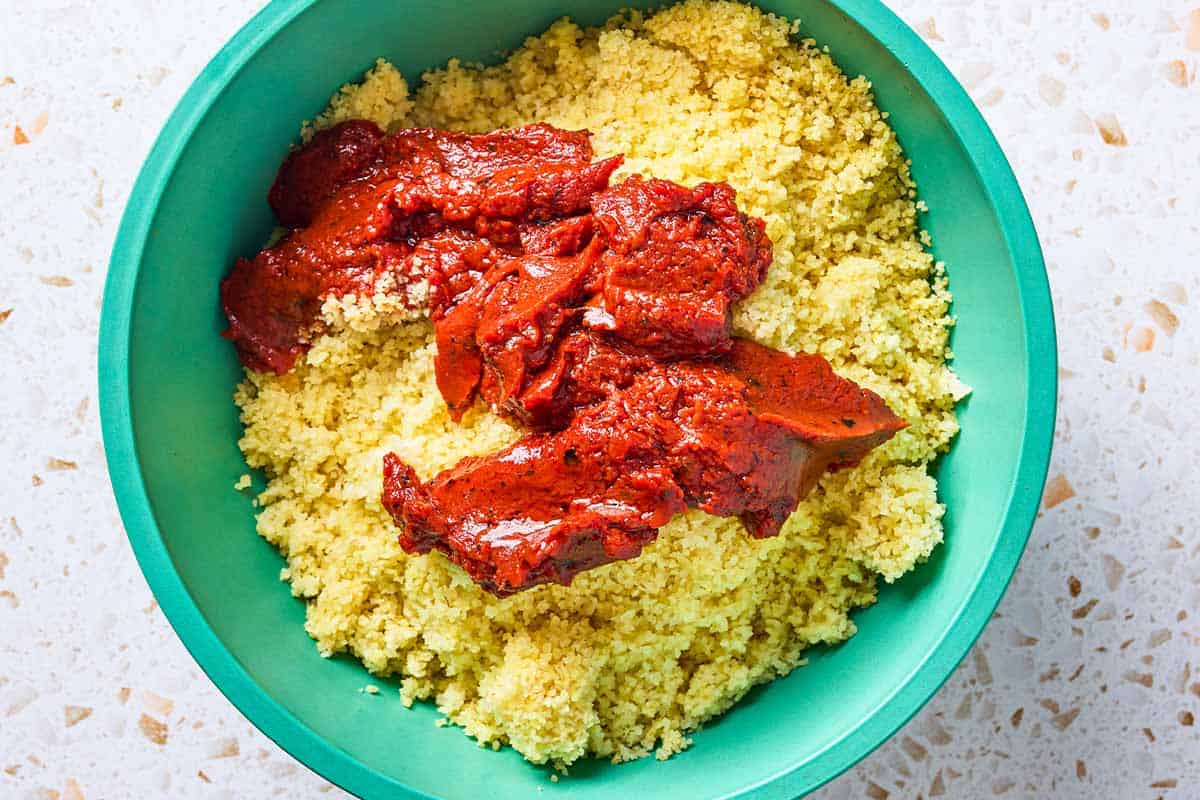 An overhead photo of the cooked bulgur and the prepared paste in a bowl just before being mixed together.