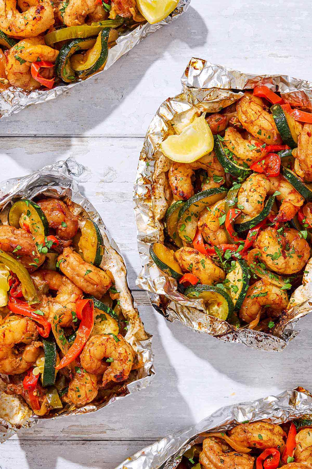 An overhead photo of 4 opened grilled shrimp foil packets.