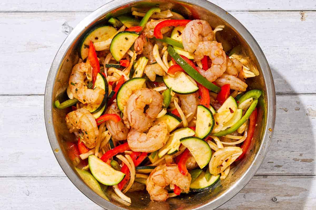 The ingredients for the grilled shrimp foil packets mixed together in a large bowl.