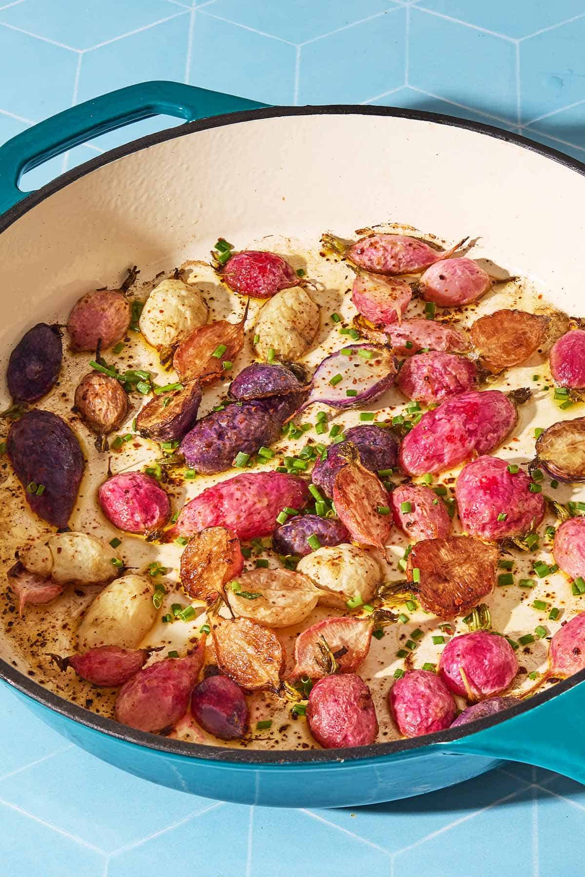 A close up of roasted radishes in a skillet garnished with chives.