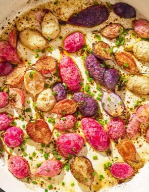 An overhead close up photo of roasted radishes in a skillet garnished with chives.
