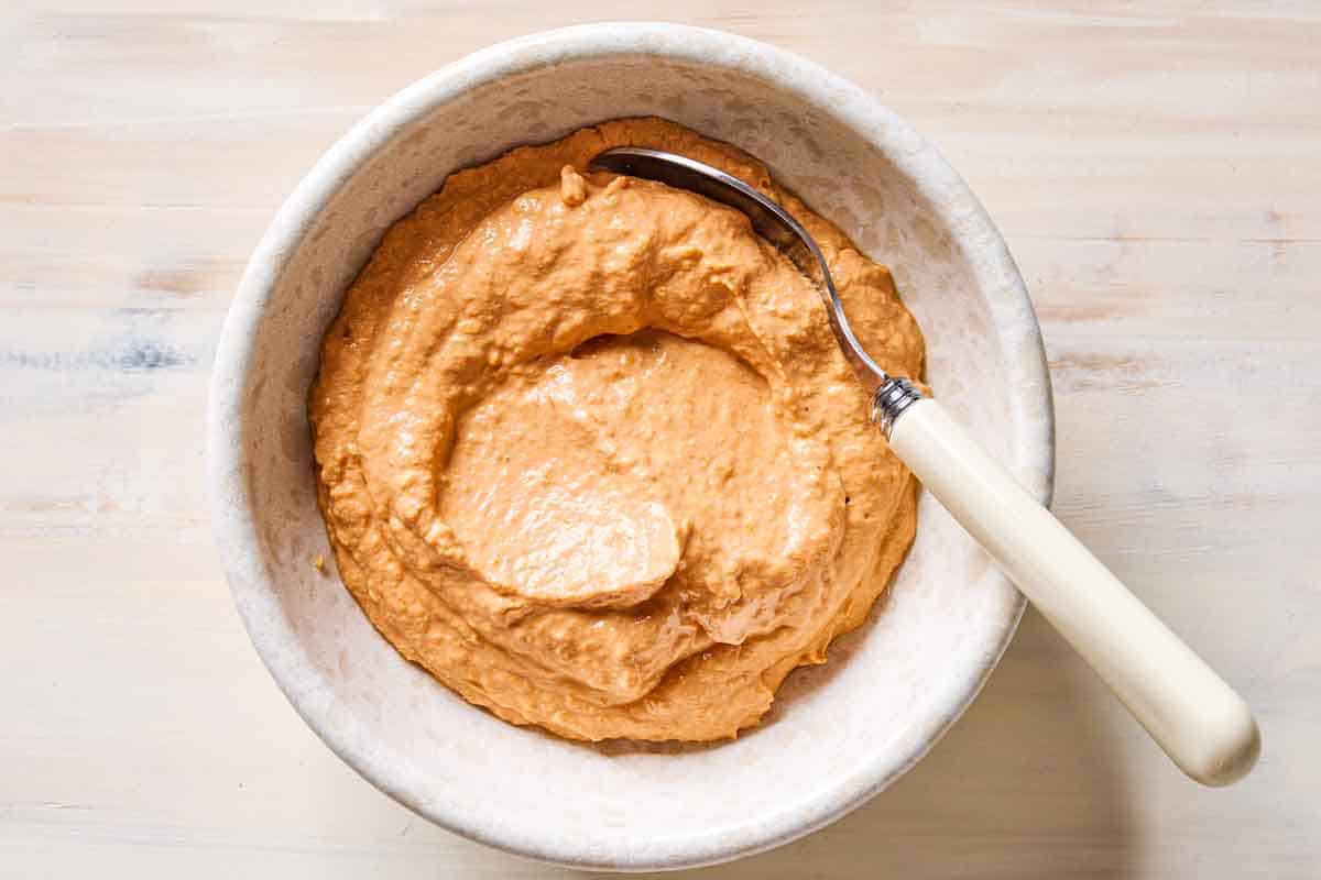 An overhead photo of a bowl of sun dried tomato yogurt dip with a spoon.