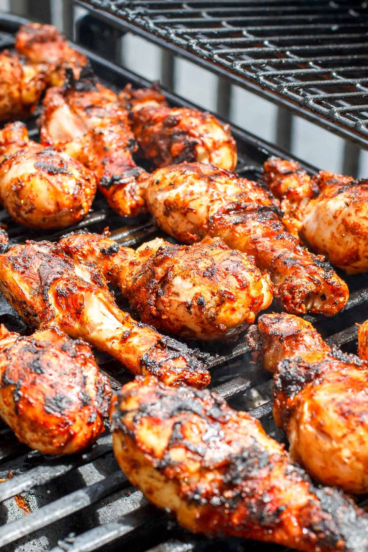 Marinated chicken drumsticks being grilled on a gas grill.