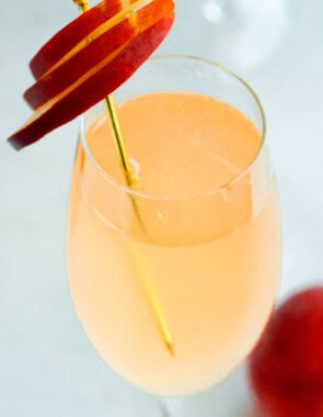 A close up of a peach bellini garnished with peach slices.