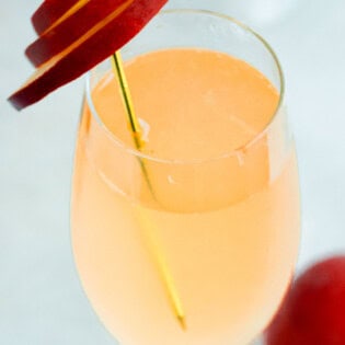 A close up of a peach bellini garnished with peach slices.