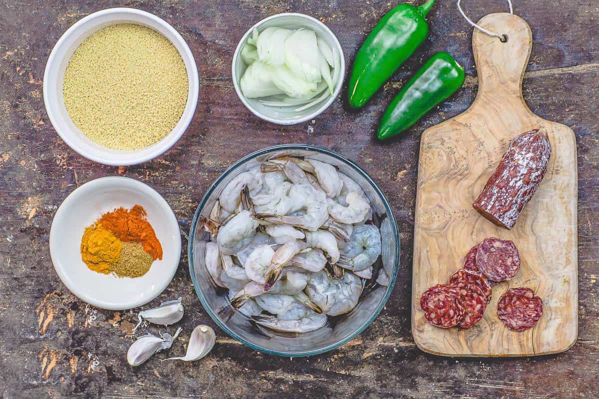 Ingredients for shrimp couscous including shrimp, couscous, garlic, jalapenos, onion, chorizo, turmeric, paprika, and cumin.
