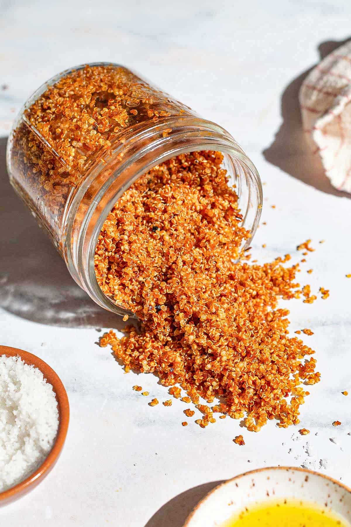 crispy quinoa spilling out of a jar laying on its side.