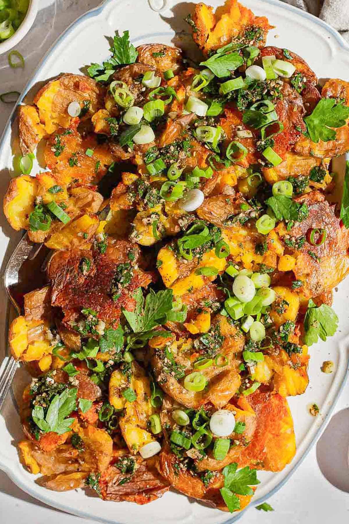 An overhead photo of crispy smashed potatoes on a serving platter.