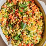 An overhead photo of grilled corn salad in a serving bowl with a spoon.